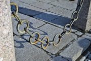 image of chain link fencing hanging between two cement posts, over slate path