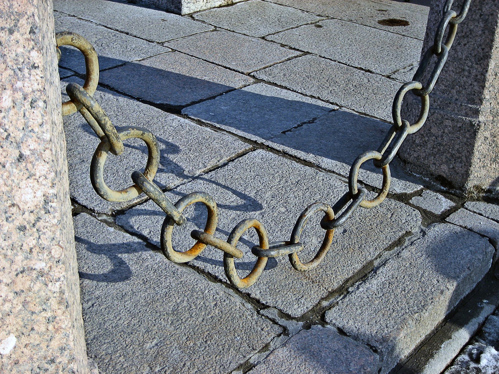 image of chain link fencing hanging between two cement posts, over slate path